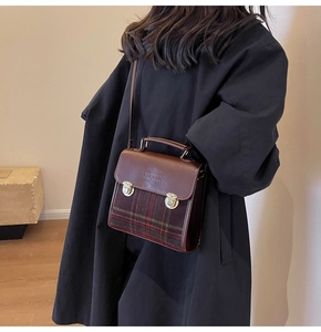 Close-up of vintage plaid patterns and metal buckle details on a brown briefcase bag