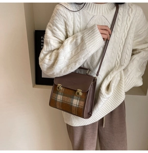 Detail of vintage crossbody bag showing contrast brown leather and plaid woolen flap