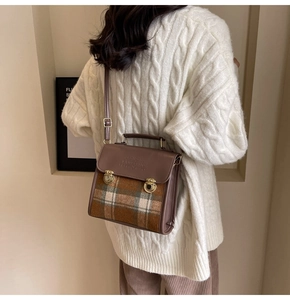 Detail of vintage briefcase bag with brown leather and plaid pattern on model's shoulder