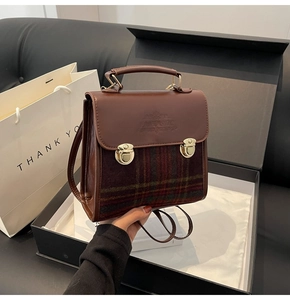 Detail of vintage briefcase bag with plaid fabric, leather handle and metal buckles