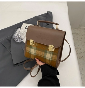 Detail of vintage briefcase with brown leather cover and colorful checkered fabric texture