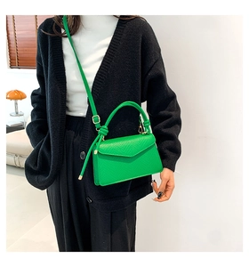 Mini borsa a tracolla in pelle verde con patta a busta e manico, indossata dalla modella