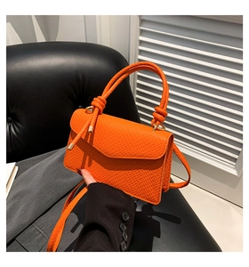 Dettaglio borsa arancione vivace con trama a lucertola e manico con nodo di design