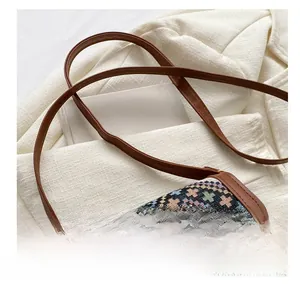 Détail d'un sac bandoulière bohème avec motifs tissés colorés et bandoulière marron élégante