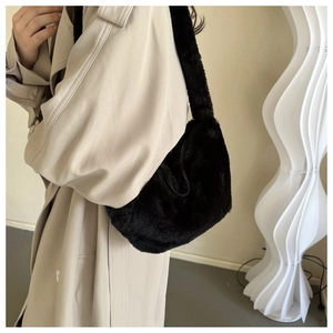 Fashionable black faux fur dumpling bag worn over the shoulder with a beige trench coat