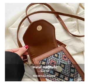 Détail d'un sac bandoulière marron avec broderie ethnique et fermoir magnétique rond