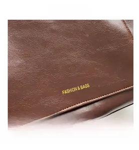 Détail du cuir marron à motif litchi avec le logo doré Fashion & Bags gravé