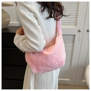 Back view of a model wearing a plush pink crescent shoulder bag with soft fuzzy texture