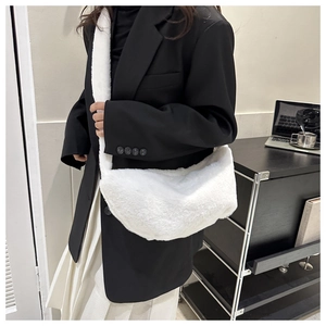 Close-up of white plush crossbody bag showing soft faux fur texture and wide shoulder strap