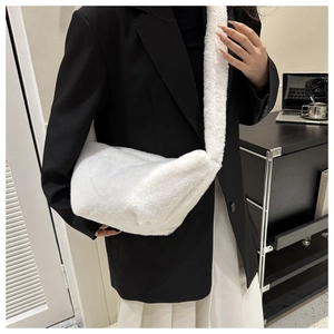 Close-up of white plush crossbody bag with wide shoulder strap worn with black blazer