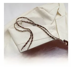 Détail du sac bandoulière en cuir brillant marron foncé avec chaîne métallique classique