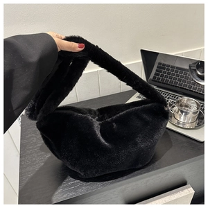 Detail of black faux fur dumpling bag showing soft plush texture and wide strap handle