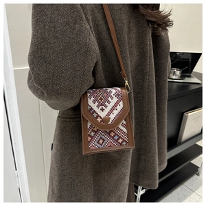 Petit sac carré brodé ethnique avec garniture en cuir porté sur un manteau