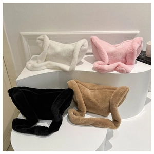 Plush crossbody bags in white, pink, black, and brown shown on a tiered minimalist display