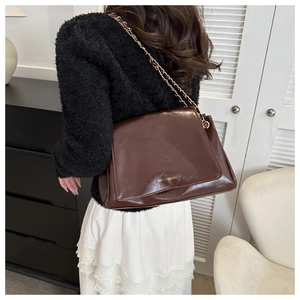 Détail du sac en cuir verni marron foncé avec bandoulière chaîne dorée et lettres