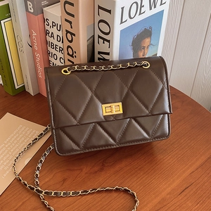 Klassische dunkelbraune Stepptasche mit goldener Kette auf einem Holztisch