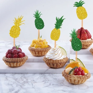 Sparkly yellow and green pineapple cupcake toppers displayed on fruit tarts