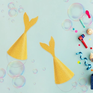 Close-up of glittery gold mermaid tail party hats with elastic bands on blue background