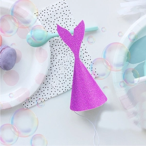 Close-up of a purple glitter mermaid tail party hat on a pastel themed table