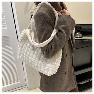 Detailed view of white pleated bubble texture tote bag on a model in brown suit