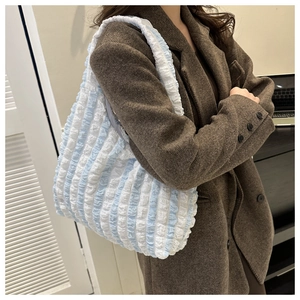 Detail of blue and white striped puffy tote bag with textured pleated fabric on a model