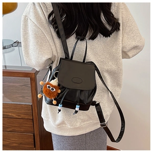 Detail of black leather mini backpack with plush lion charm and beaded drawstring tassels