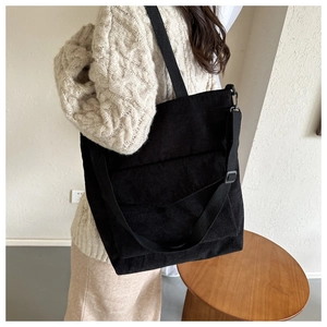 Close-up of black corduroy tote bag showing ribbed texture and front pocket detail