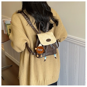 Detail of contrast color mini backpack in dark brown and beige on a yellow sweater