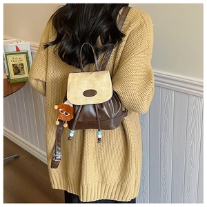 Detail of vintage color-blocked bucket backpack with a plush lion pendant on the side
