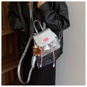 Silver metallic mini backpack featuring pink logo plaque and cute plush monster charm