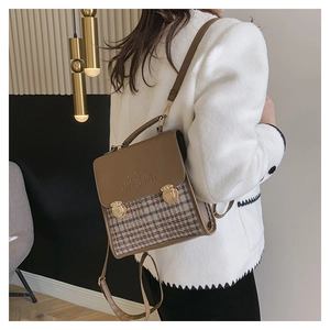 Dettaglio della borsa vintage a quadri con patta in pelle marrone e fibbie metalliche