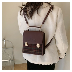 Dettaglio dello zaino vintage in pelle marrone e tessuto scozzese con fibbie d'oro