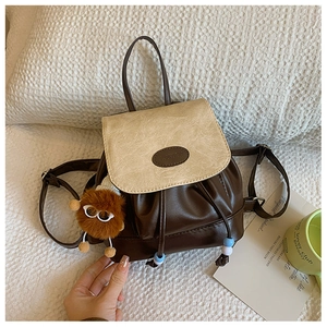 Detail of retro mini backpack with drawstring, leather texture and plush monster charm