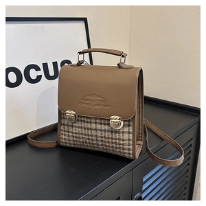 Dettaglio della cucitura in pelle vintage e della trama del tessuto a quadri della borsa