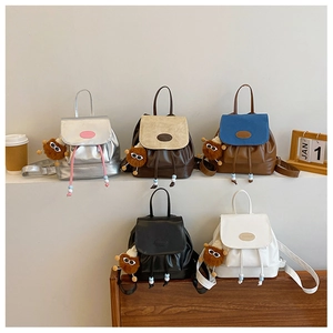 Close-up of five mini drawstring backpacks in various colors with cute plush pendants