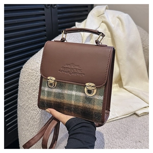 Dettaglio borsa vintage a quadri con finiture in pelle marrone e fibbie metalliche