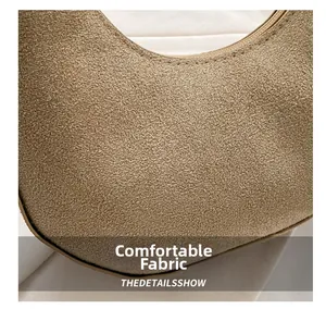 Detailed macro shot of the beige suede texture and stitching on the crescent handbag