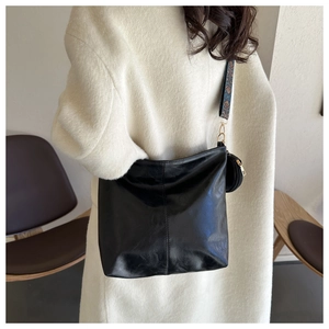 Detail of a black leather tote bag with vintage jacquard strap on a female model