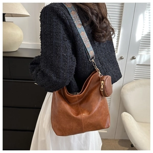 Detail view of brown leather hobo bag with a stylish colorful patterned wide shoulder strap