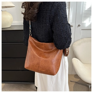 Brown large capacity tote bag shown on model in a modern indoor lifestyle setting