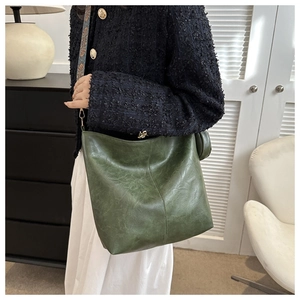 Detail of dark green bucket bag with embroidered wide strap and matching round coin purse
