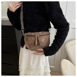 Détail d'un sac selle vintage marron avec bandoulière ethnique large et zip doré