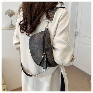 Détail d'un sac bandoulière gris rétro avec une sangle tissée au motif bohème