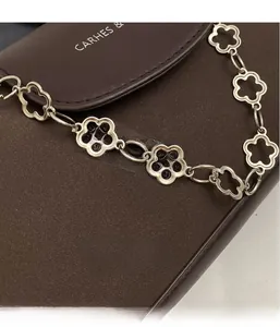 Close-up of vintage silver hollow flower chain strap on a textured brown leather shoulder bag