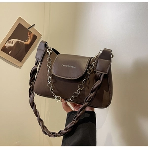 Detail of dark brown leather crossbody bag with braided strap and silver floral chain
