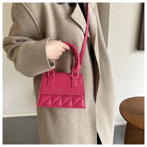 Magenta quilted mini handbag with gold logo detail worn by a model in a beige wool coat