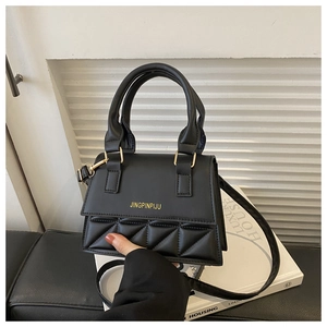 Detail of black quilted leather crossbody bag featuring gold lettering and metal clasp