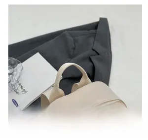 Close-up of comfortable fabric handle and dual metal zippers on beige mini backpack