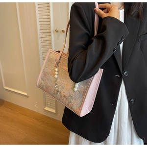 Détail du sac bandoulière rose avec chaîne de perles et motif de peinture à l'huile