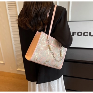 Gros plan du sac cabas en jacquard rose avec motifs dorés et chaîne décorative en perles